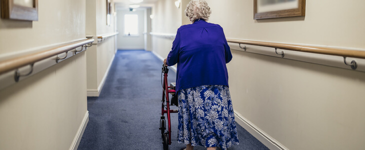 elderly woman walking down a hallway with a walker nursing home accidents