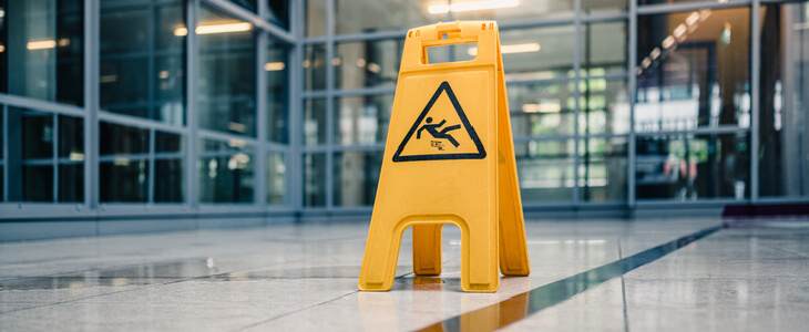 slip and fall yellow sign over puddle in a room with glass windows