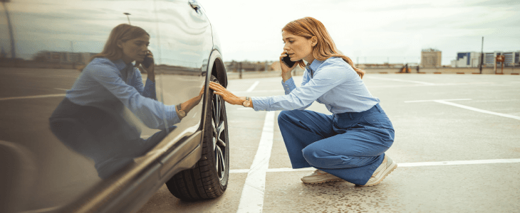 a women inspecting her front tired after a car accident in new york